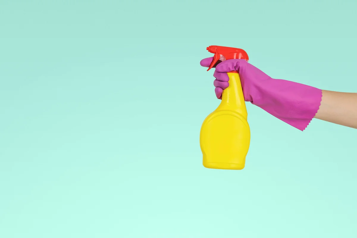 person holding yellow plastic spray bottle - beginner guide to buying nontoxic cleaning supplies