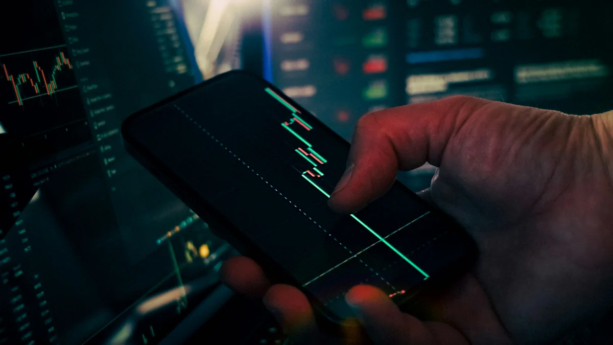 Hand smartphone trading chart technology finance background. Close-up of a person analyzing candlestick stock chart - financial growth portfolio - Are expensive daily products worth the investment