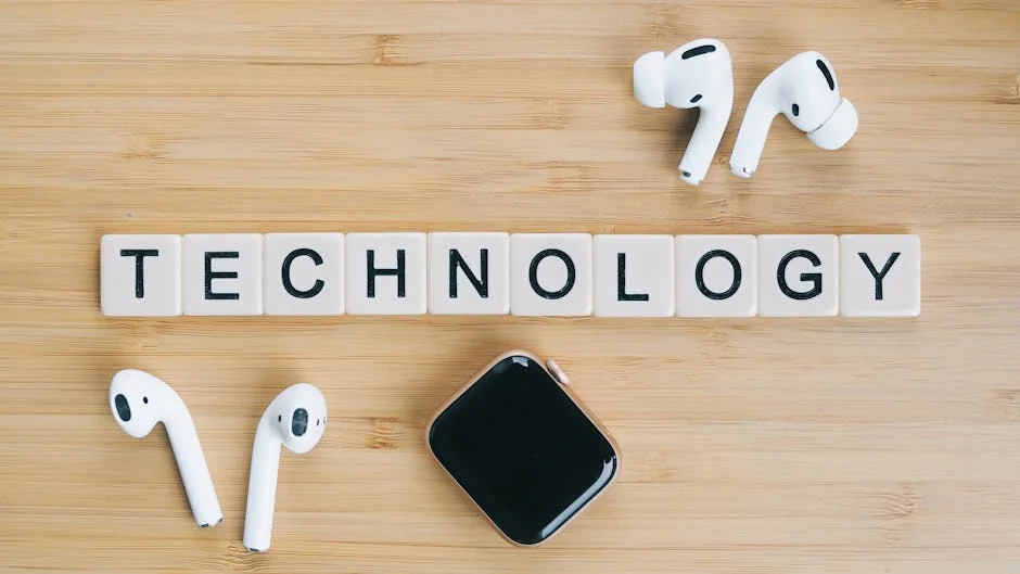 Flat lay of wireless earphones and smartwatch next to TECHNOLOGY tiles on a wooden table. - factors to consider before upgrading your daily tech gadgets
