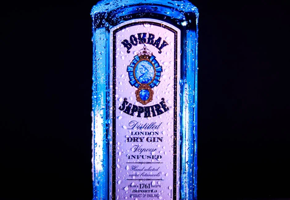 High-quality image of Bombay Sapphire gin bottle with water droplets, showcasing its distinct design. - honest comparison of premium vs generic household brands