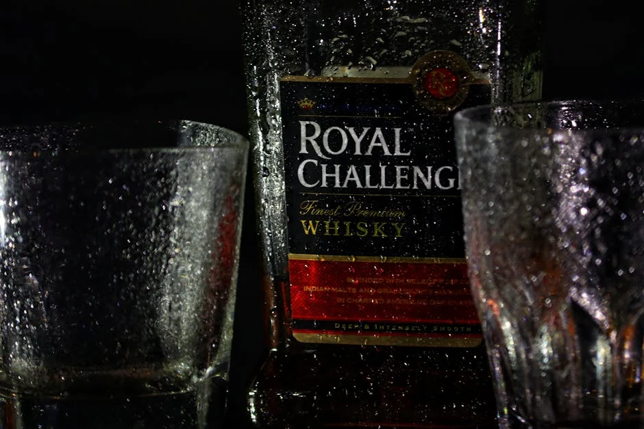 Close-up shot of Royal Challenge whiskey bottle with glasses. - honest comparison of premium vs generic household brands
