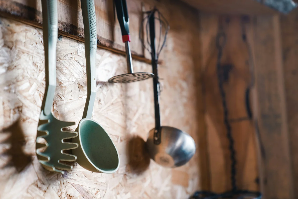 a wooden wall with pots and pans hanging on it - longterm durability reviews of everyday kitchen tools