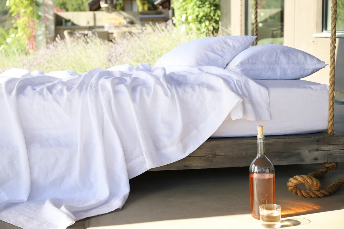 two white pillows on bed and glass of bottle near drinking glass on floor - what to look for when purchasing highquality bed linens