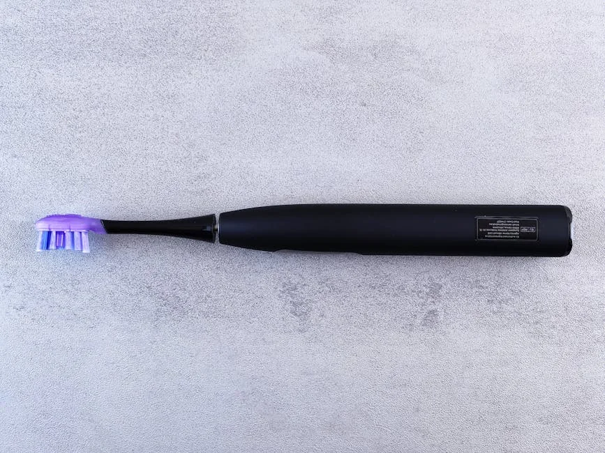 A sleek black electric toothbrush with a purple head lies on a textured concrete surface. - performance analysis of the top electric toothbrushes