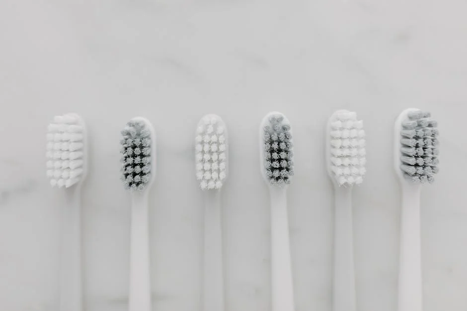 A clean, minimalist top view of six white toothbrushes on a marble surface. - performance analysis of the top electric toothbrushes