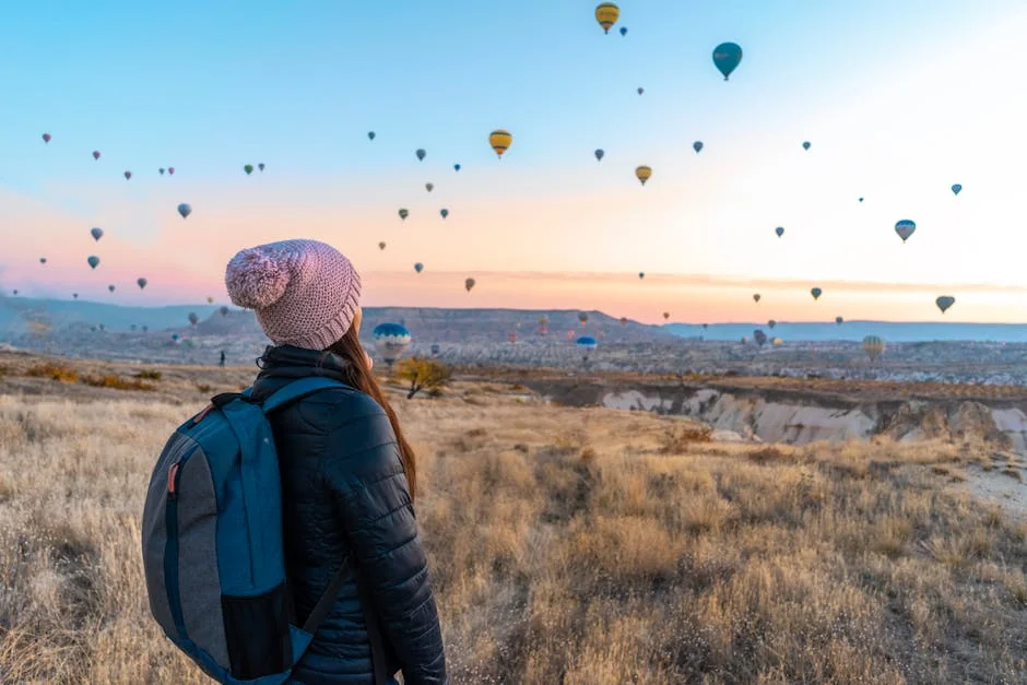 Woman watching hot air balloons in Cappadocia at sunrise, a popular travel destination. - adventure vacation destination - Rare and useful travel essentials for frequent commuters